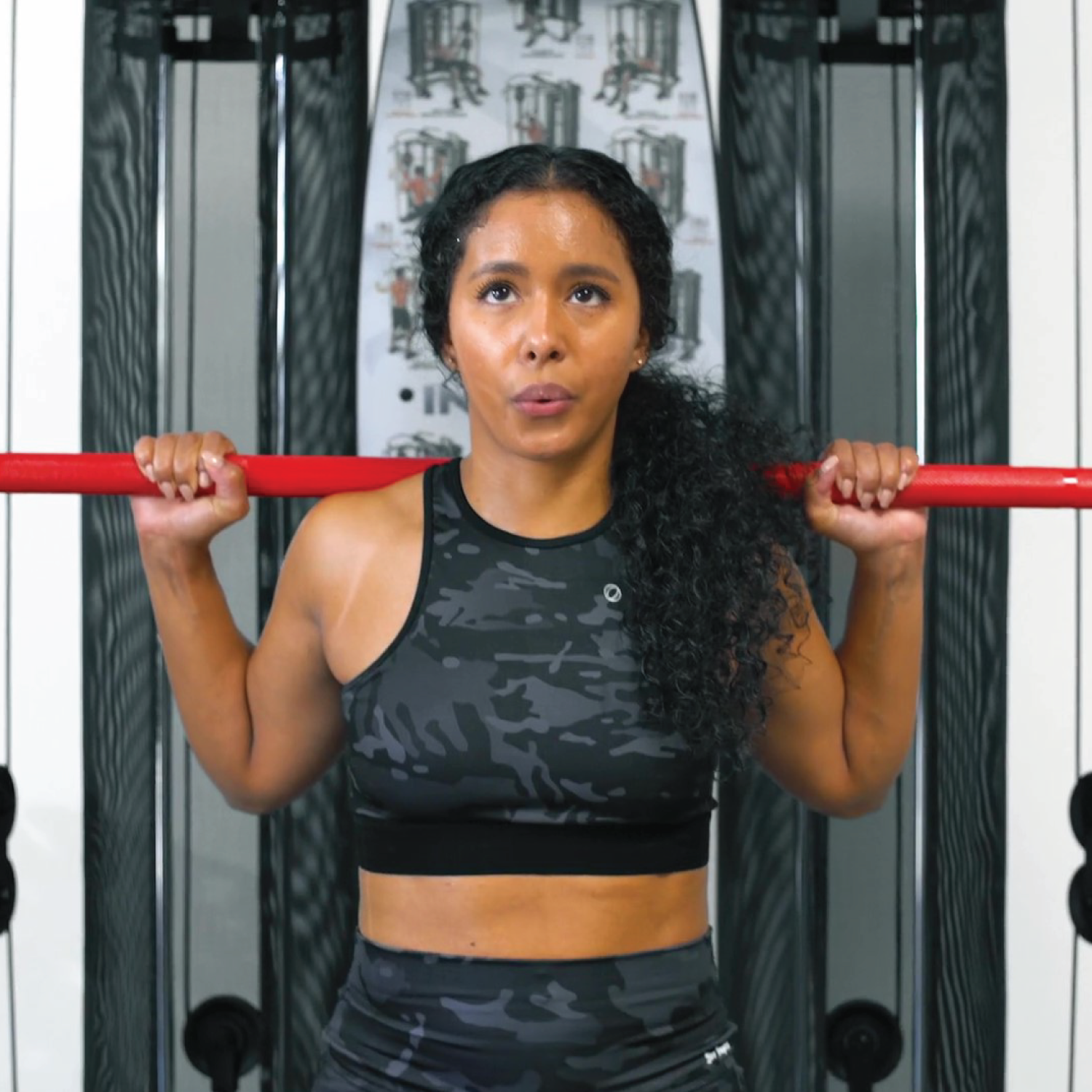 Configuration de la cage Inspire SCS pour les squats, montrant les supports de sécurité et la barre olympique.