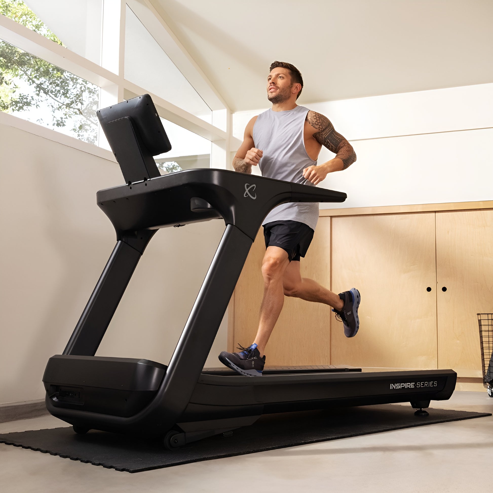 Utilisation du tapis roulant Inspire T7S dans un décor de gym à domicile (home gym) moderne et lumineux.