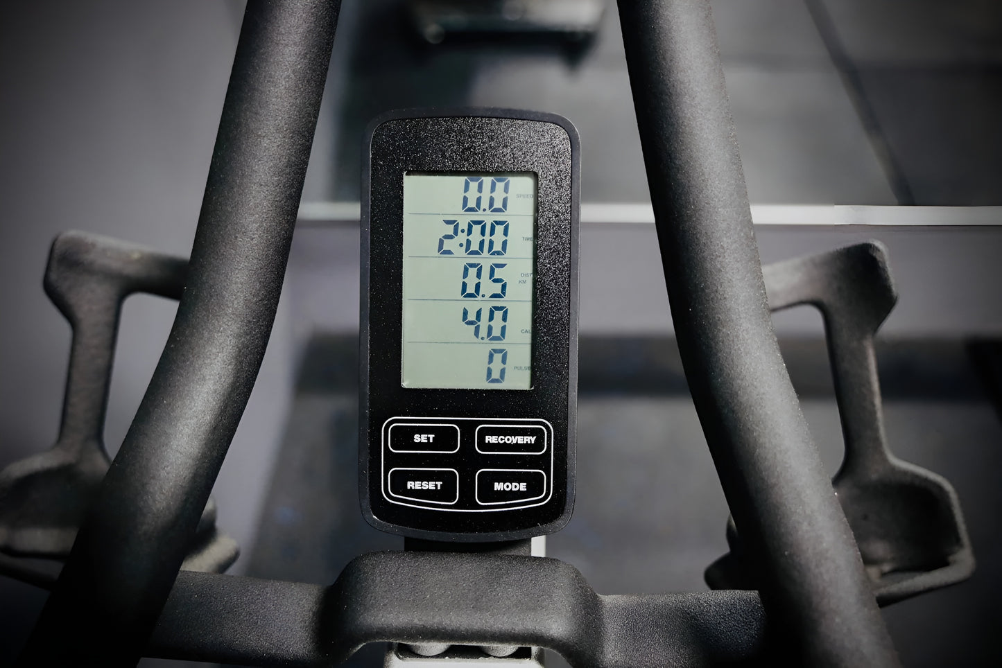 Gros plan sur la console numérique LCD du vélo S3, affichant le temps, la distance et les calories, entourée par les poignées du guidon.
