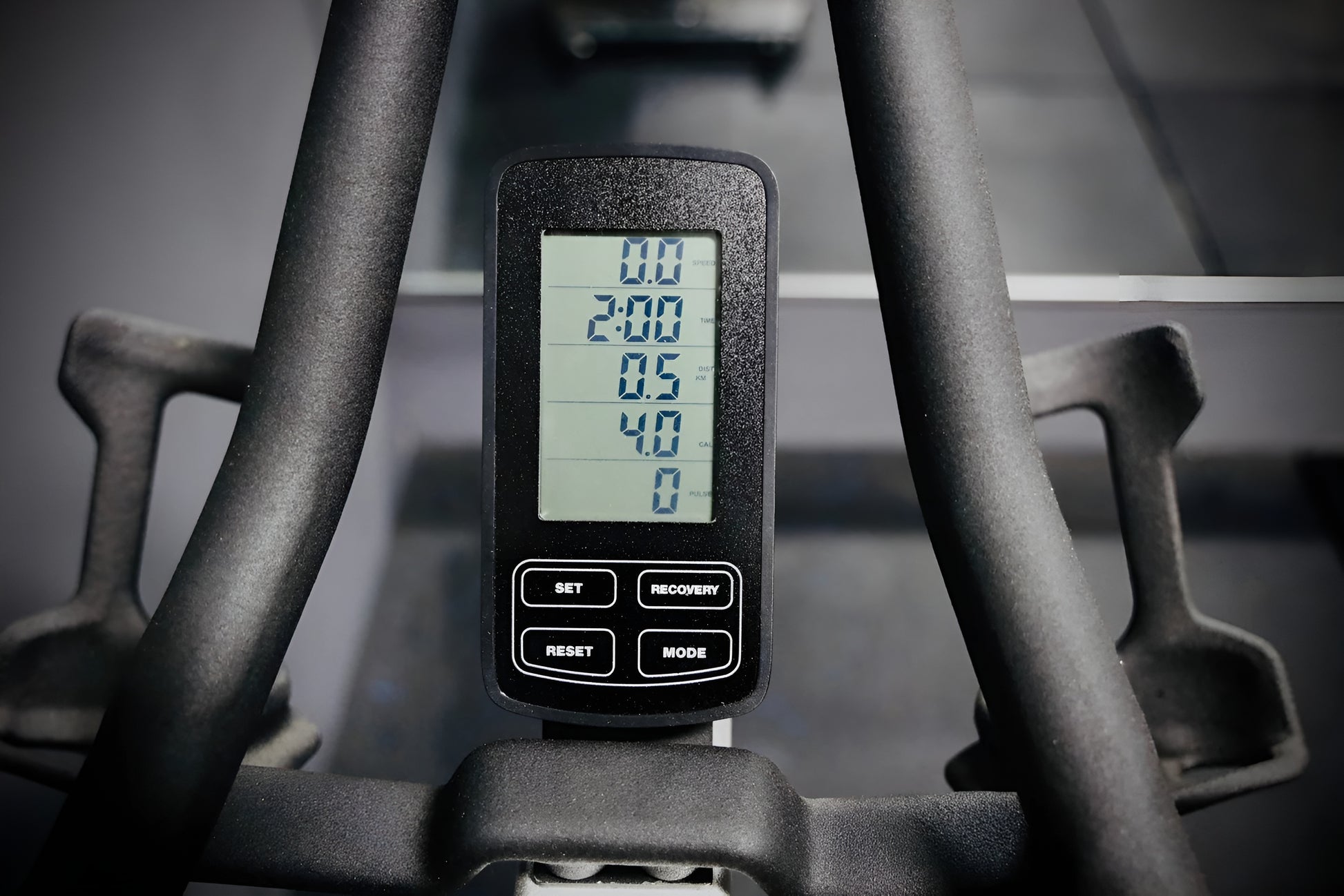 Gros plan sur la console numérique LCD du vélo S3, affichant le temps, la distance et les calories, entourée par les poignées du guidon.