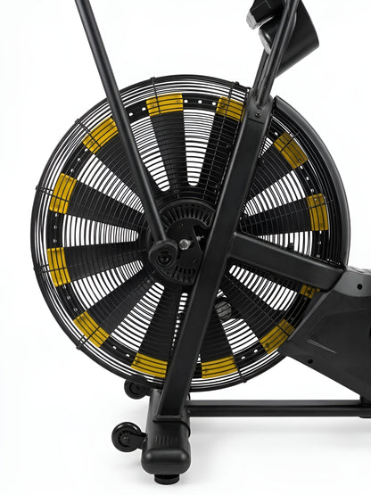 Un gros plan sur la grande roue à aubes de l'Airbike HALT3R Fitness. On y voit les pales inclinées qui créent la résistance à l'air, ainsi que le moyeu central et la cage de protection en métal.